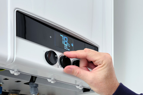 Man stelt temperatuur in op moderne digitale thermostaat in woonkamer