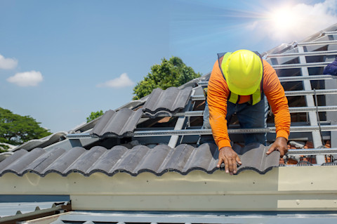 Dakspecialist legt nieuwe dakpannen van keramiek op een dak van een woning
