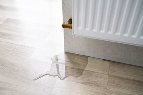 Beschadigde laminaatvloer door lekkage van vloerverwarming, zichtbaar opgezwollen hout.