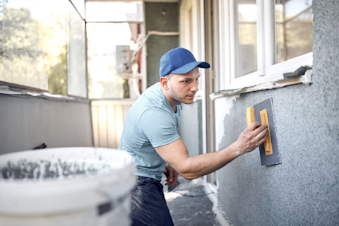 vakman werkt aan gevel van een huis