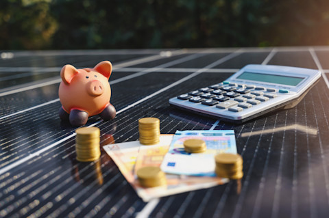 Gestapeld geld met zonnepanelen benadrukt de besparing op energiekosten dankzij duurzame stroomopwekking.