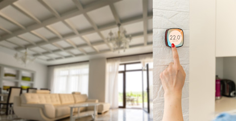 Een man stelt de temperatuur in via een slimme thermostaat op een smartphone.