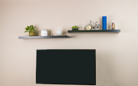 Zwarte blinde planken gemonteerd boven de tv voor het neerzetten van decoratie