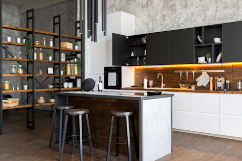 Luxe loftkeuken met betonlook vloer, zwart kookeiland en open indeling met veel lichtinval.