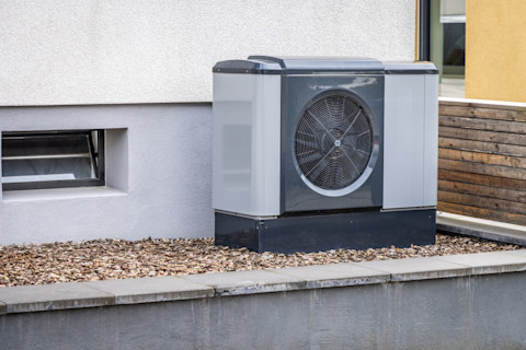 Moderne luchtbron warmtepomp gemonteerd aan de buitenmuur van een woning.