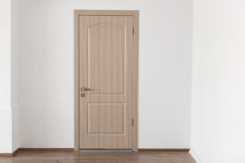 Houten binnendeur in gesloten positie tegen een witte muur, minimalistisch interieur.