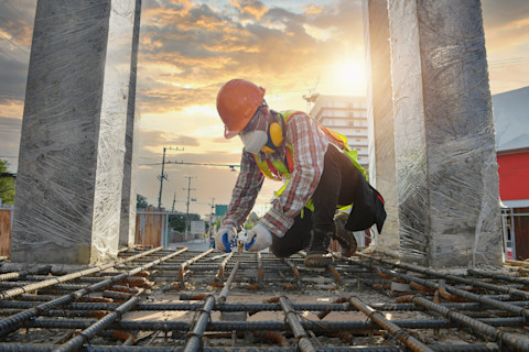  Bouwvakker werkt aan ijzeren staven bij de bouw van een fundering.