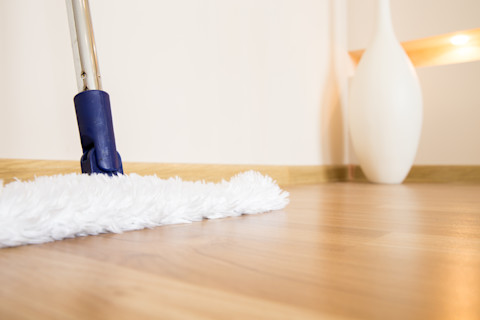 Witte dweil op houten vloer toont een glanzend schoonmaakresultaat in een moderne woning.