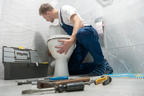 een vakman plaatst een nieuwe wc pot tijdens een toilet renovatie