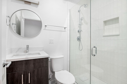 Moderne inloopdouche in een kleine badkamer die is uitgerust met een toilet en wastafel