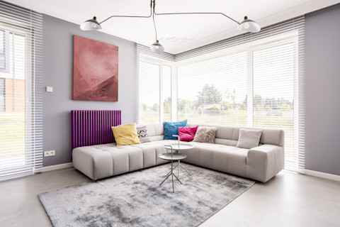 Twee kleine tafeltjes op zacht vloerkleed bij radiatorombouw – interieur met een radiatorombouw, lichte meubels en een knus vloerkleed.