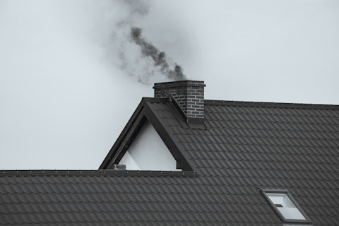 Donkere rook stijgt op uit een schoorsteen door verstopping of creosootophoping.