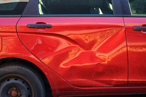 Deur van een rode auto heeft een deur als gevolg van een aanrijding