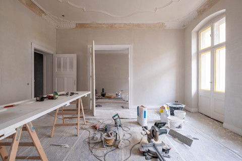 Een woning die verbouwd wordt. Er staan materialen en gereedschappen in de kamer.