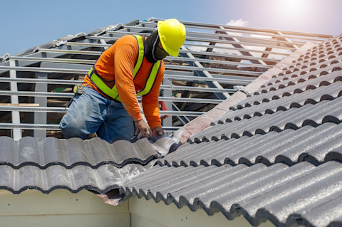 Dakspecialist is bezig met het vervangen van een dak met een nieuwe houten constructie en dakpannen