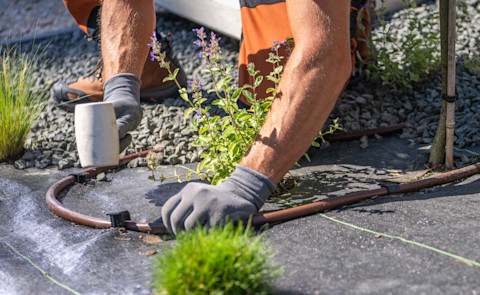 Hovenier verbindt onderdelen van een irrigatiesysteem tijdens de aanleg van tuin drainage.
