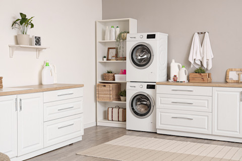 Witte wasmachines in een lichte bijkeuken met open planken en decoratieve accenten voor een functionele uitstraling.