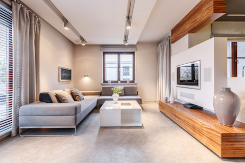 Ruime moderne woonkamer met grote grijze hoekbank en een verlaagd plafond.