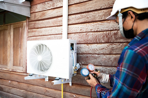Airco specialist checkt de airco van een huis om te bepalen of deze bijgevuld moet worden.