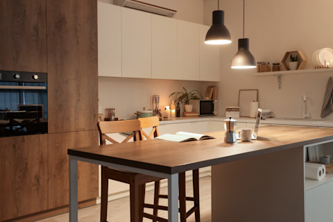 Warm verlichte keuken met gloeiende lampen boven het aanrecht, voor een gezellige sfeer.