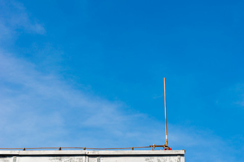 Een blauwe lucht met een bliksemafleider op een stukje dak