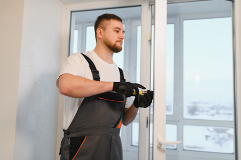 Monteur plaatst nieuw raamkozijn in bakstenen muur van woning