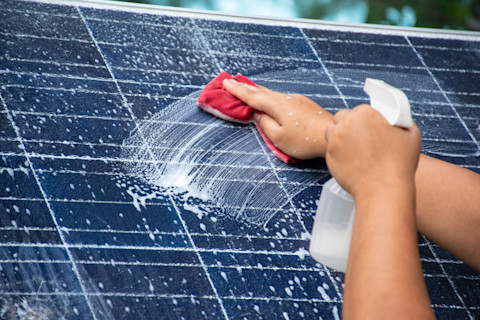 Mini-zonnepaneel wordt schoongespoten met water tijdens het schoonmaken.