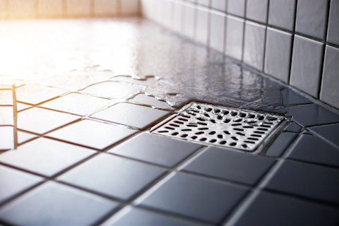 Water stroomt naar beneden door een strak afvoervierkant in de douche, symbool van hygiëne en goede doorstroming.