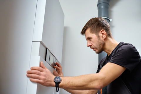 Monteur die het bedieningspaneel van een warmtepomp instelt tijdens de installatie in een woning.