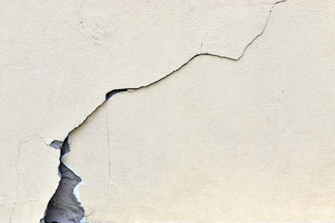  Grote, lange scheur in een gele betonnen vloer, duidelijk zichtbaar over de volledige lengte.  