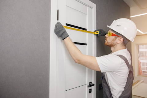 Timmerman meet nauwkeurig een deur af tijdens het installatieproces in een woning.
