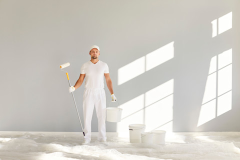 Schilder verft een muur met een roller in een modern appartement
