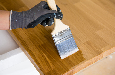 Persoon brengt olie aan op houten keukenblad ter bescherming en onderhoud.
