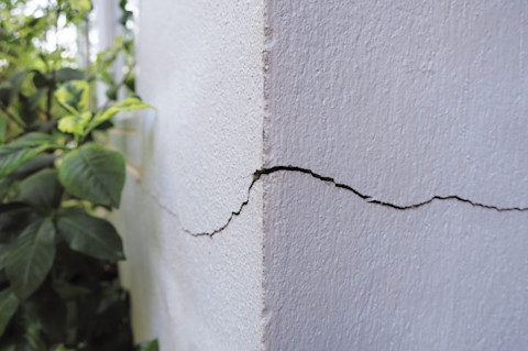 Diepe scheur in een betonnen buitenmuur, duidelijk zichtbaar structureel probleem.