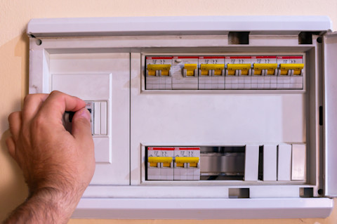 Hand van een installateur inspecteert een moderne groepenkast met bedrading en schakelaars.