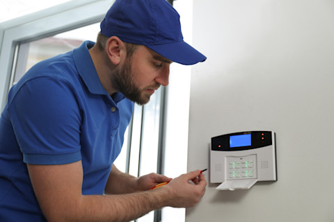 Elektricien installeert alarm systeem bij een glazen deur