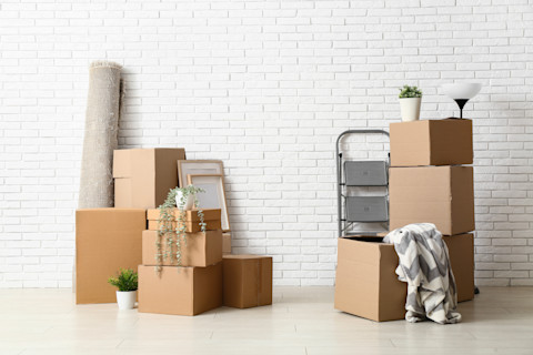 Verhuisdozen staan klaar tegen een witte muur voor een georganiseerde verhuizing.