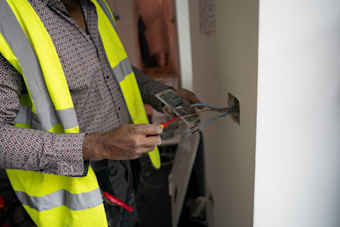 Elektricien werkt aan de bedrading in huis voor het plaatsen van een laadpaal thuis