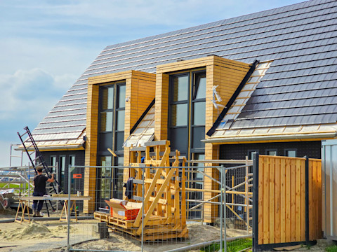 Nieuwbouwwijk in aanbouw met prefab elementen in typisch Nederlandse buitenwijk, overzicht bouwplaats.