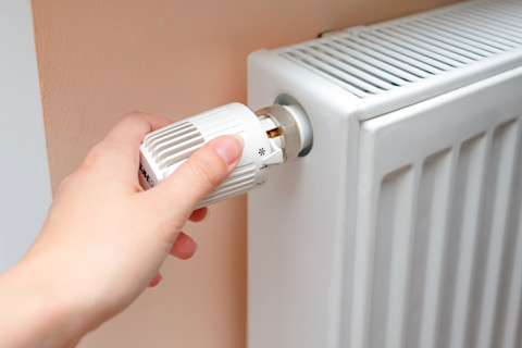 Hand draait aan radiator knop van witte radiator
