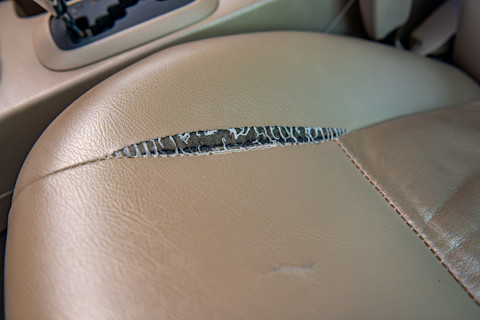 De beige leren bekleding van de auto heeft een scheur en moet worden hersteld