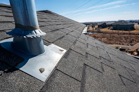 Dakdoorvoer met ventilatieopening op een schuin dak, afgedicht met siliconenkit.  