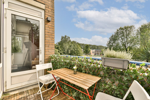 Charmant balkon met moderne meubels en weelderig groen, ideaal voor kleine buitenruimtes.