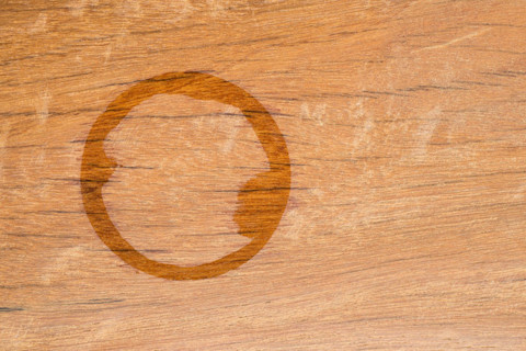 Watervlekken zichtbaar op een houten tafelblad, duidelijke verkleuring door vocht.  
