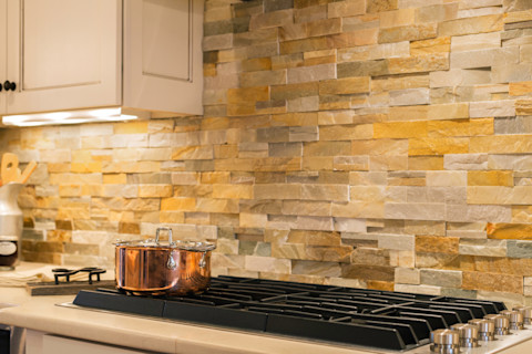 Moderne keuken met stenen achterwand en koperen pannenset voor stijl en functionaliteit.
