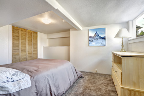 Gezellig slaapkamerinterieur met laag plafond en zachtbruin kleurenpalet.