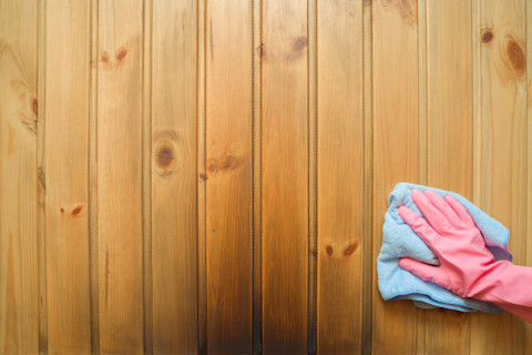 Hand in rubberen handschoen veegt roetvlekken van een witte muur als gevolg van rooklekkage.