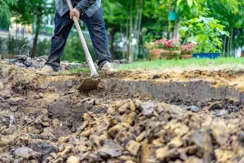 vakman verwijderd grond en grasmat uit een tuin met professioneel gereedschap