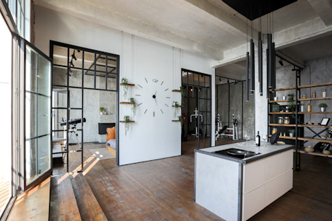 Lichte loftstudio met open keuken, betonnen muren en minimalistische inrichting.