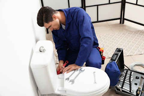 badkamer installateur installeert een wit toilet in een badkamer